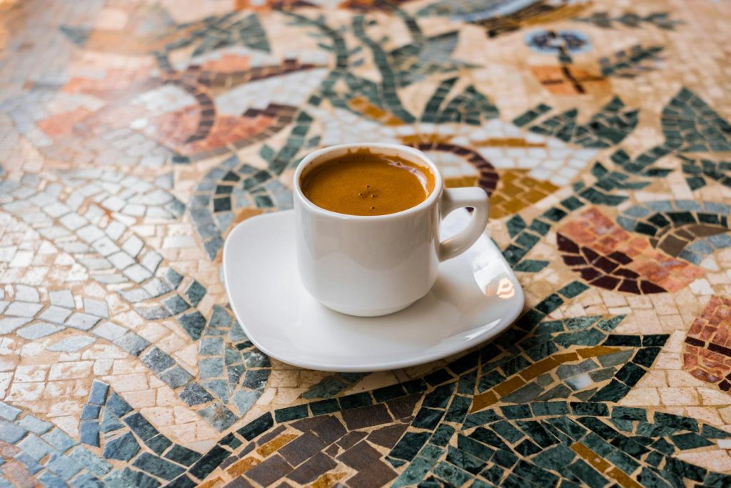 coffee origins, White espresso cup on a vibrant mosaic table, perfect for coffee enthusiasts.