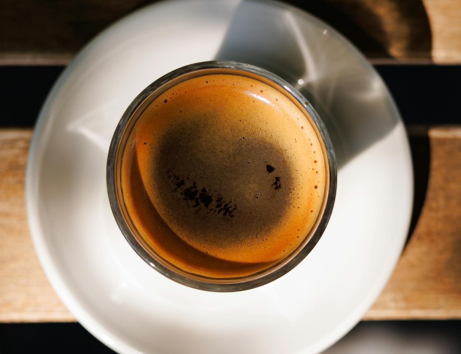 A close-up shot of a steaming hot espresso in a glass cup, casting shadows.