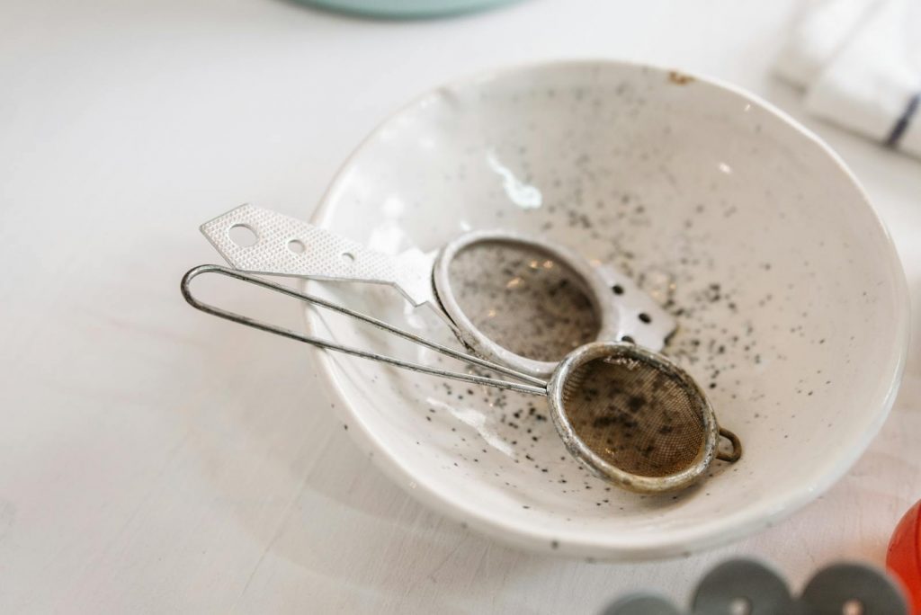 Detail of used kitchen sieve in a speckled ceramic bowl, conveying a rustic kitchen atmosphere. Easy Way to Make Coffee Without Coffee Maker